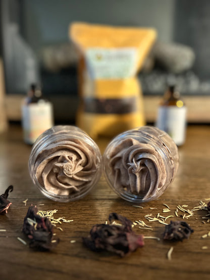 Two swirls of chocolate mousse in clear jars with a blurred background of bottles and a bag.