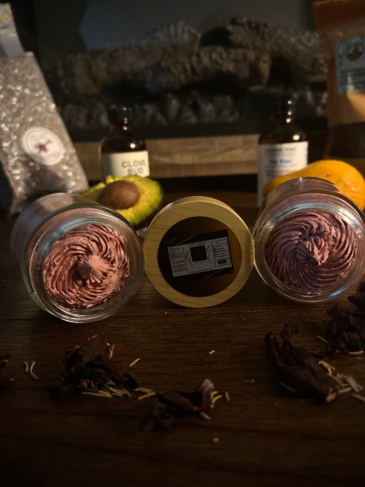 Two whipped body butters in jars with dried spices on a wooden surface.